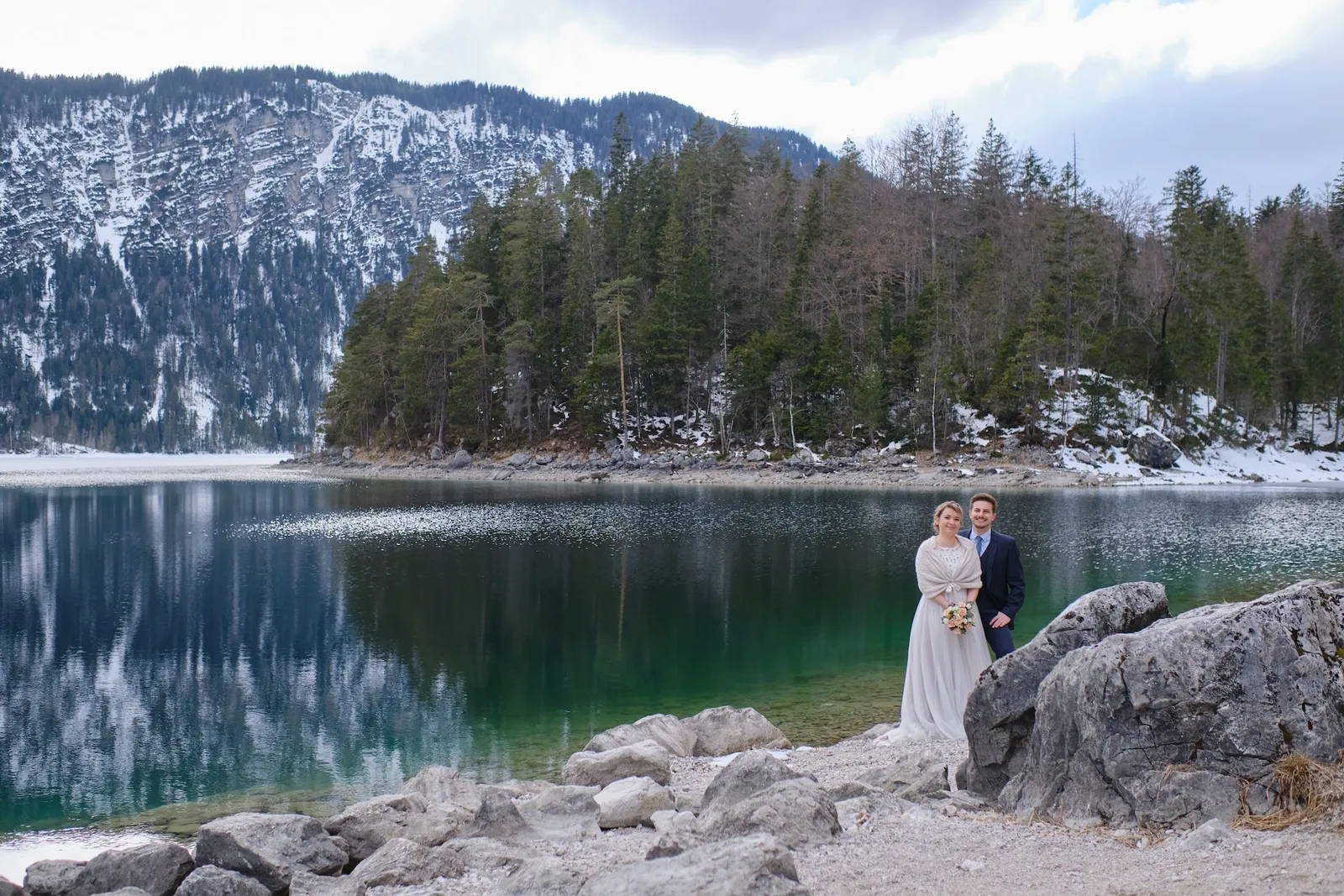 Brautpaar klein auf einem Felsen am winterlichen Eibsee, weites Bergpanorama – After Wedding Christina & Florian, Eibsee