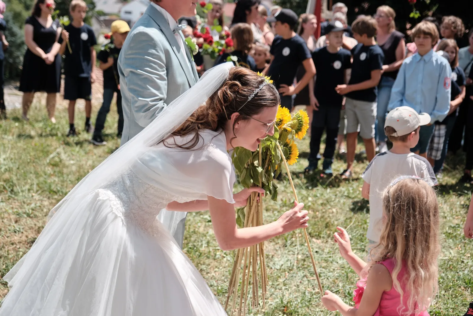 Ronja schenkt einem Kind eine Sonnenblume aus ihrem Strauß – Hochzeit Ronja & Markus, Buchloe