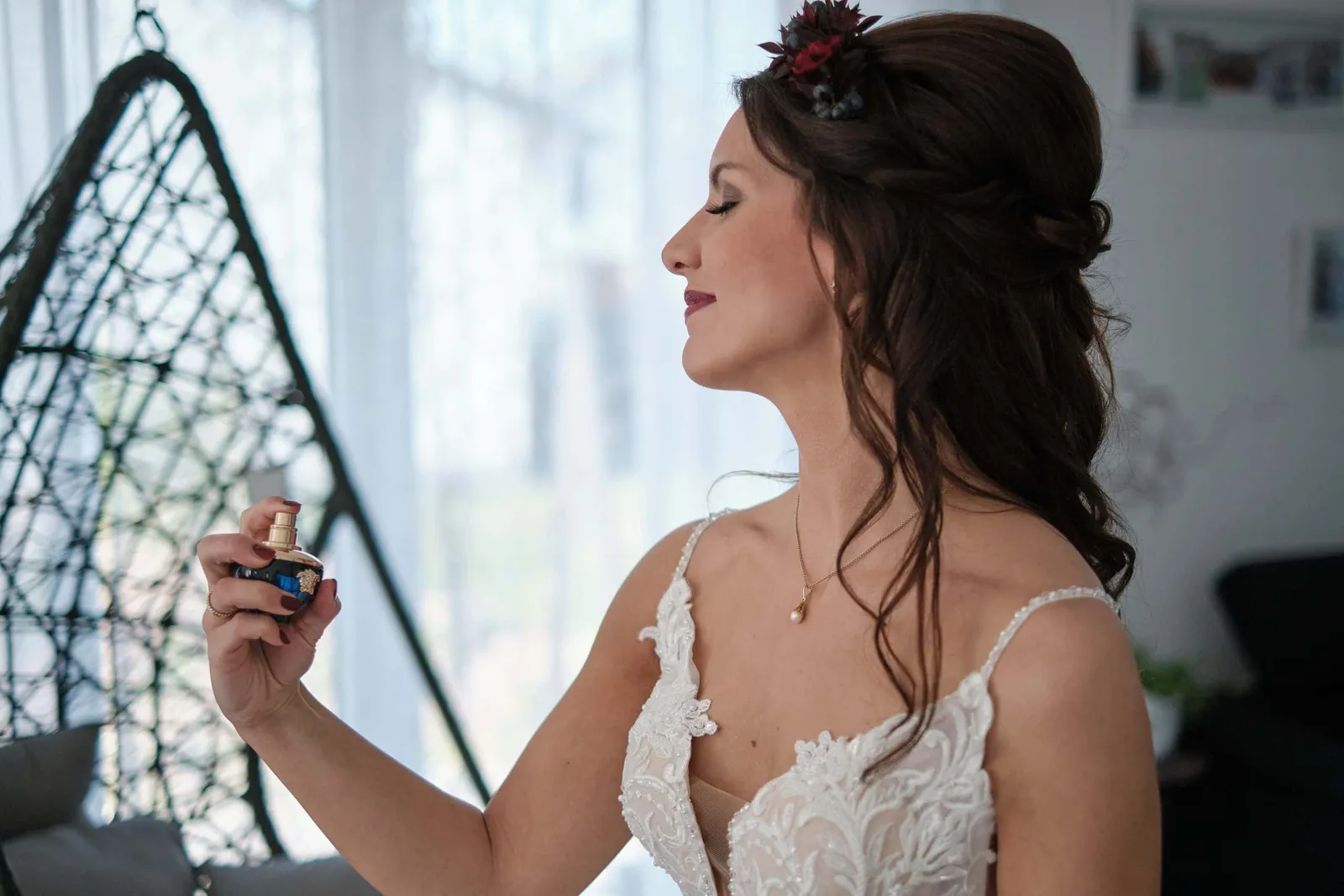 Braut trägt Parfüm auf, mit Blumenschmuck im Haar – Hochzeit Charly & Moritz, Herrenhaus Bannacker