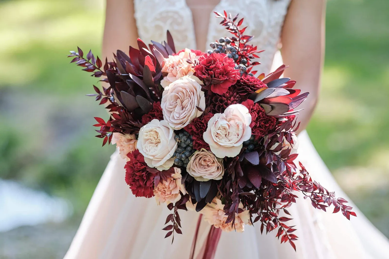 Brautstrauß mit dunkelroten und hellen Rosen vor dem Brautkleid – Hochzeit Charly & Moritz, Herrenhaus Bannacker