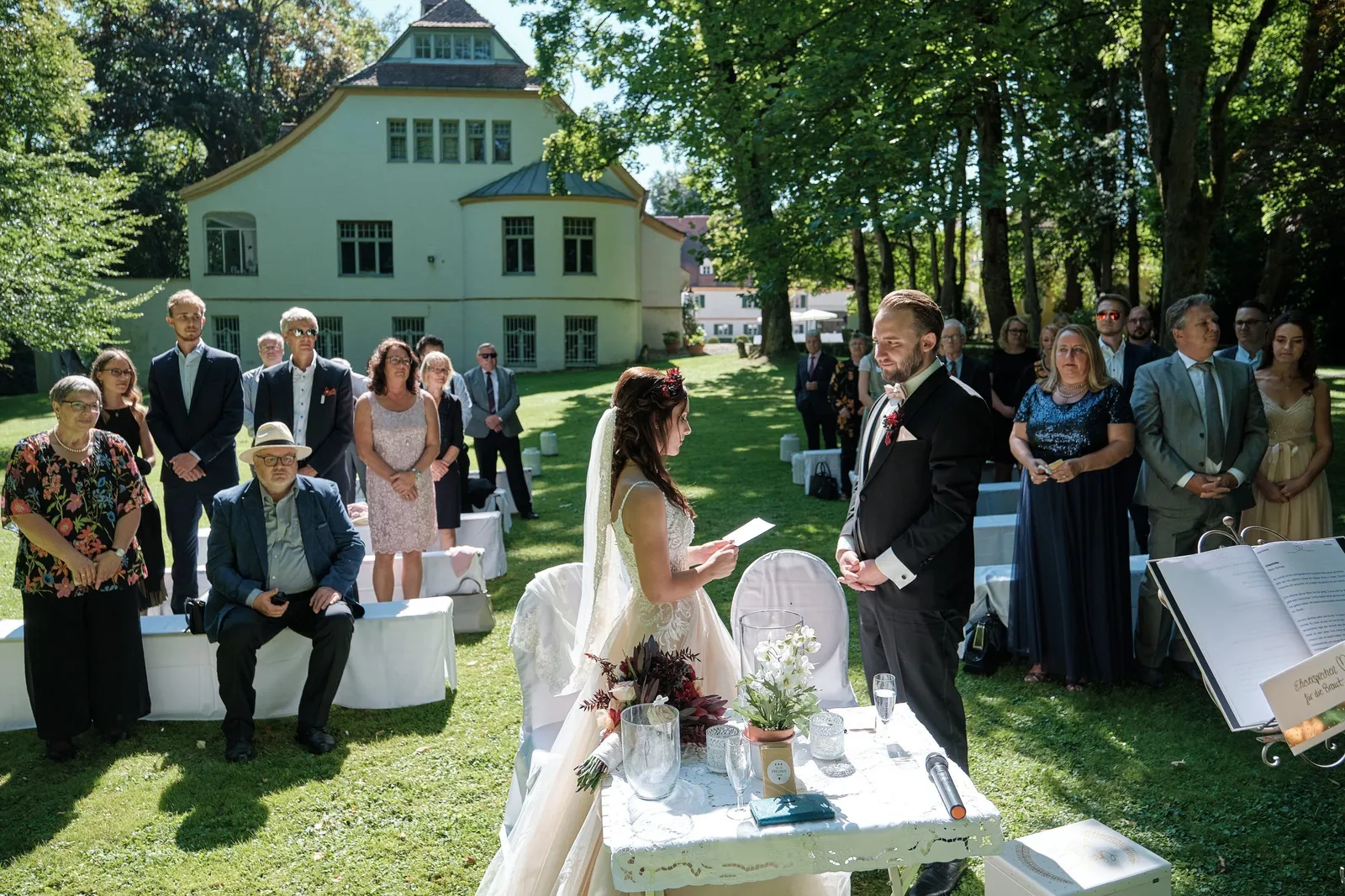 Freie Trauung im Garten vor dem Herrenhaus mit stehenden Gästen – Hochzeit Charly & Moritz, Herrenhaus Bannacker