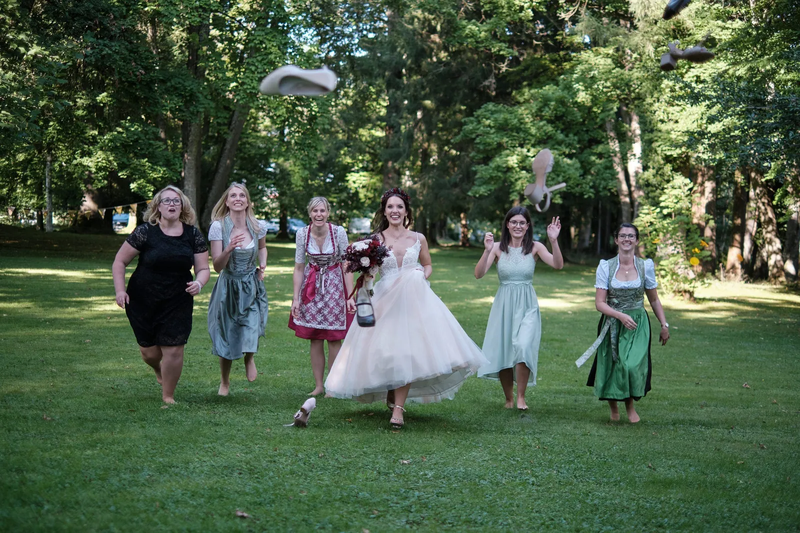 Braut läuft mit Freundinnen in Dirndln über den Rasen – Hochzeit Charly & Moritz, Herrenhaus Bannacker
