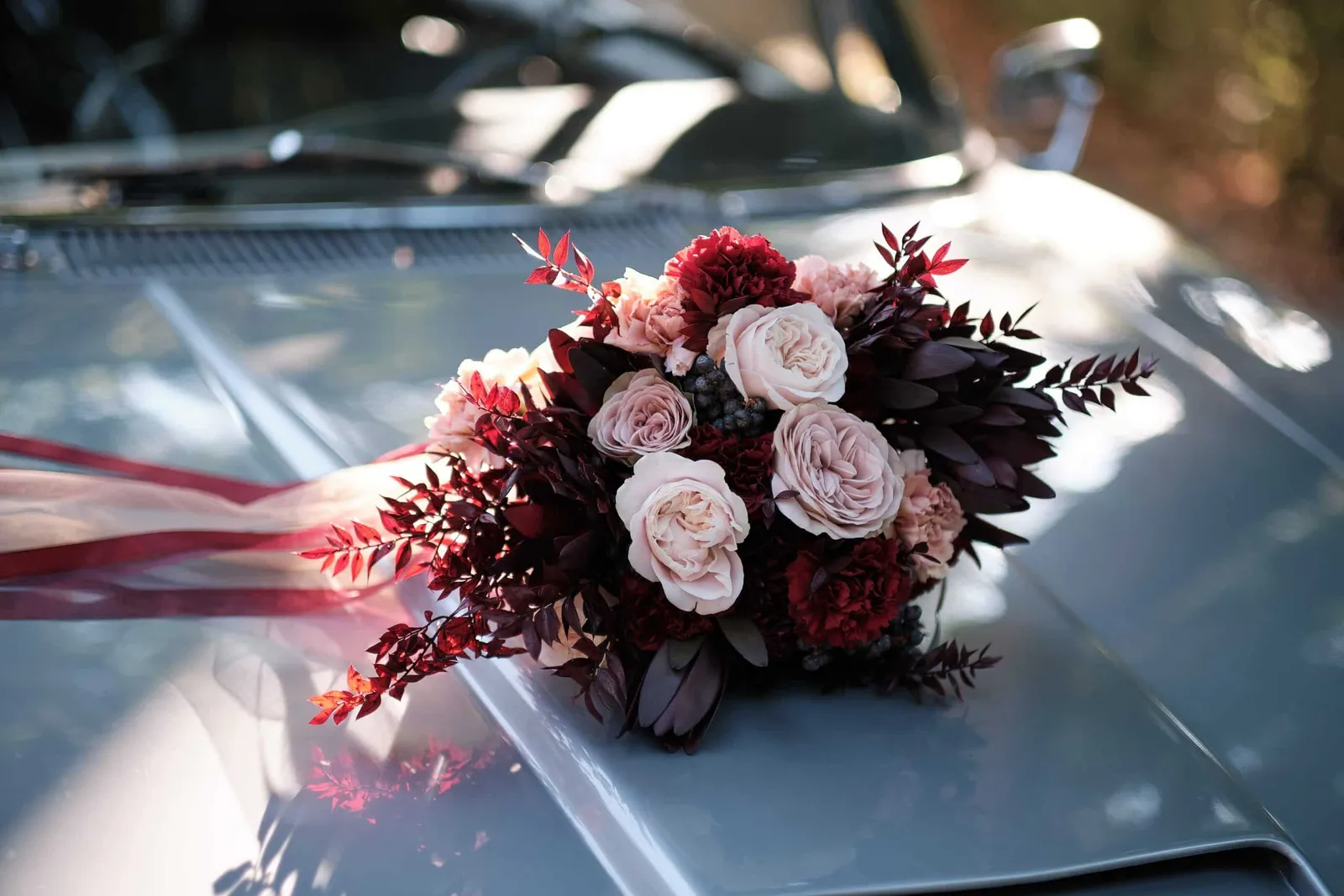 Brautstrauß mit dunkelroten Rosen auf der Motorhaube eines Oldtimers – Hochzeit Charly & Moritz, Herrenhaus Bannacker
