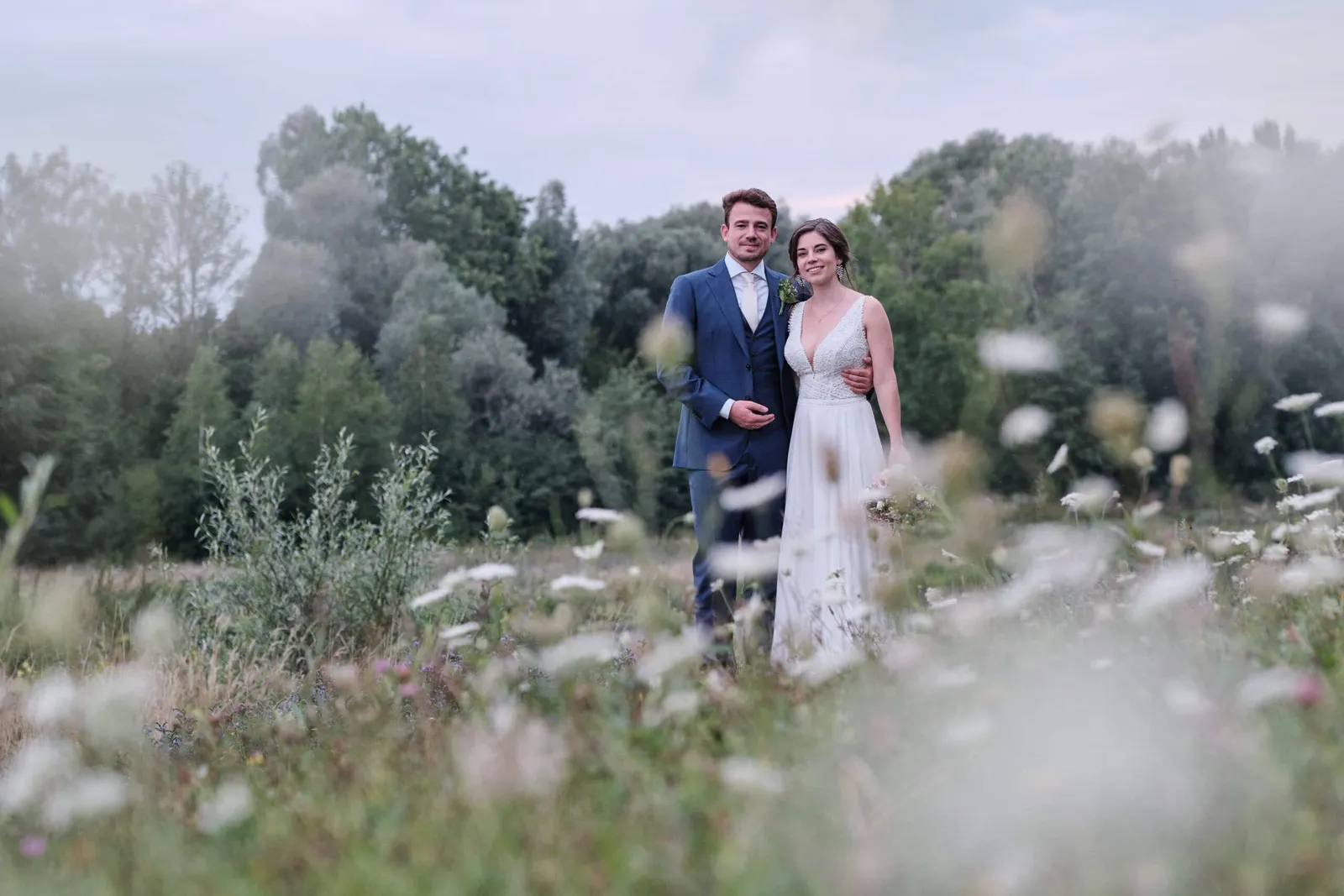 Brautpaar steht in einer Blumenwiese und blickt in die Kamera – Hochzeit Hanna & Tobi