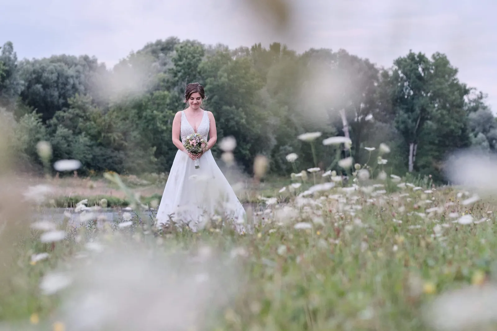 Braut mit Brautstrauß allein in einer Wildblumenwiese – Hochzeit Hanna & Tobi