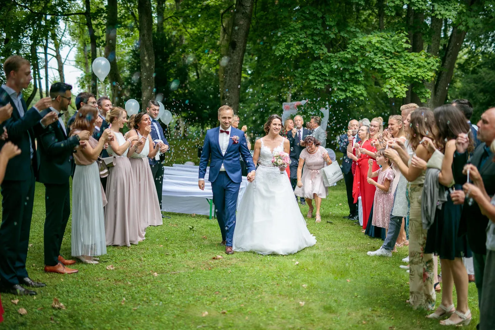 Auszug des Brautpaars zwischen jubelnden Gästen nach der freien Trauung – Hochzeit Julia & Phil, Herrenhaus Bannacker
