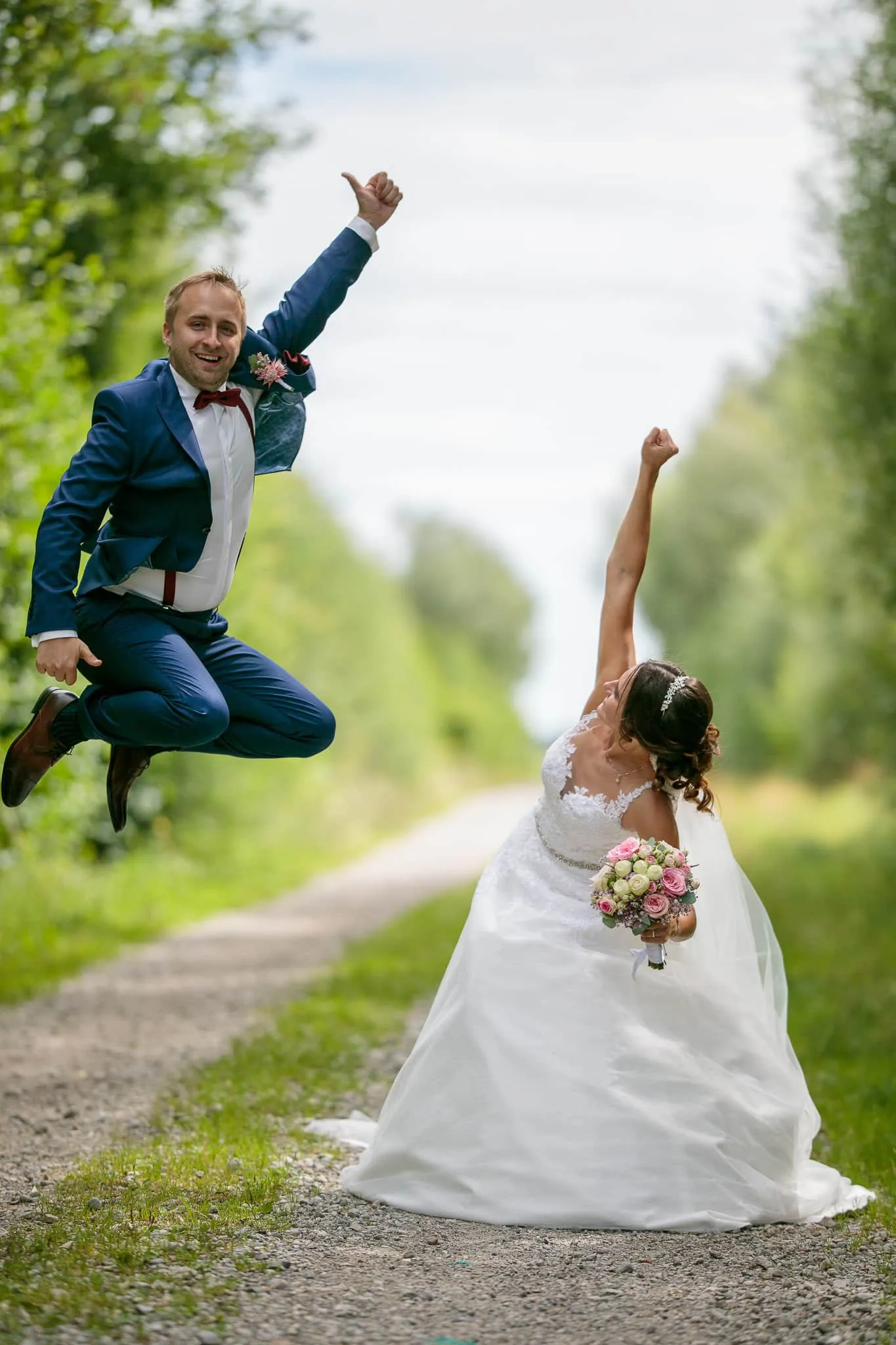 Brautpaar springt auf einem Feldweg in die Luft – Hochzeit Julia & Phil