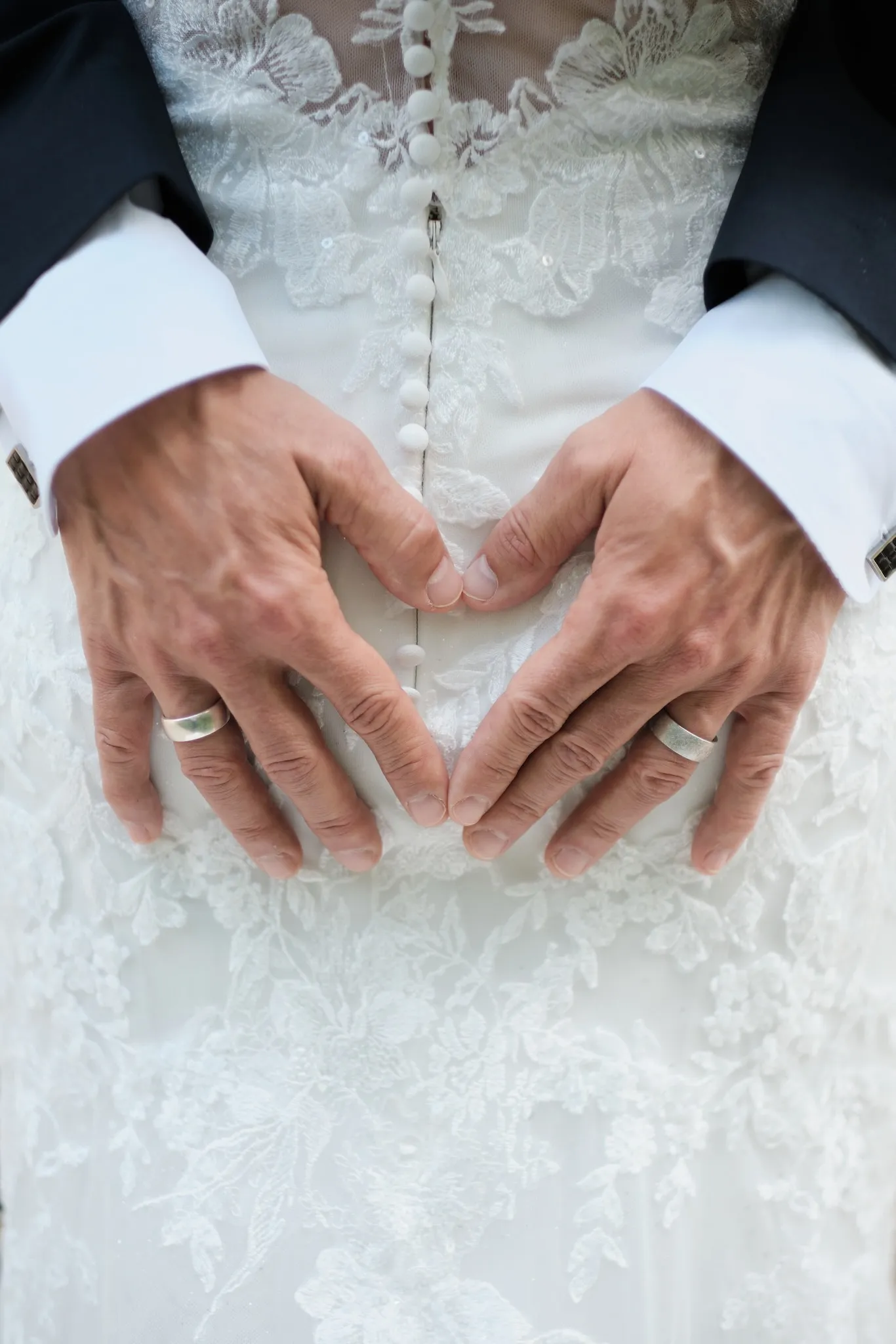 Hände in Herzform vor Tanjas Kleid, Eheringe sichtbar – Hochzeit Markus & Tanja, Königsbrunner Heide