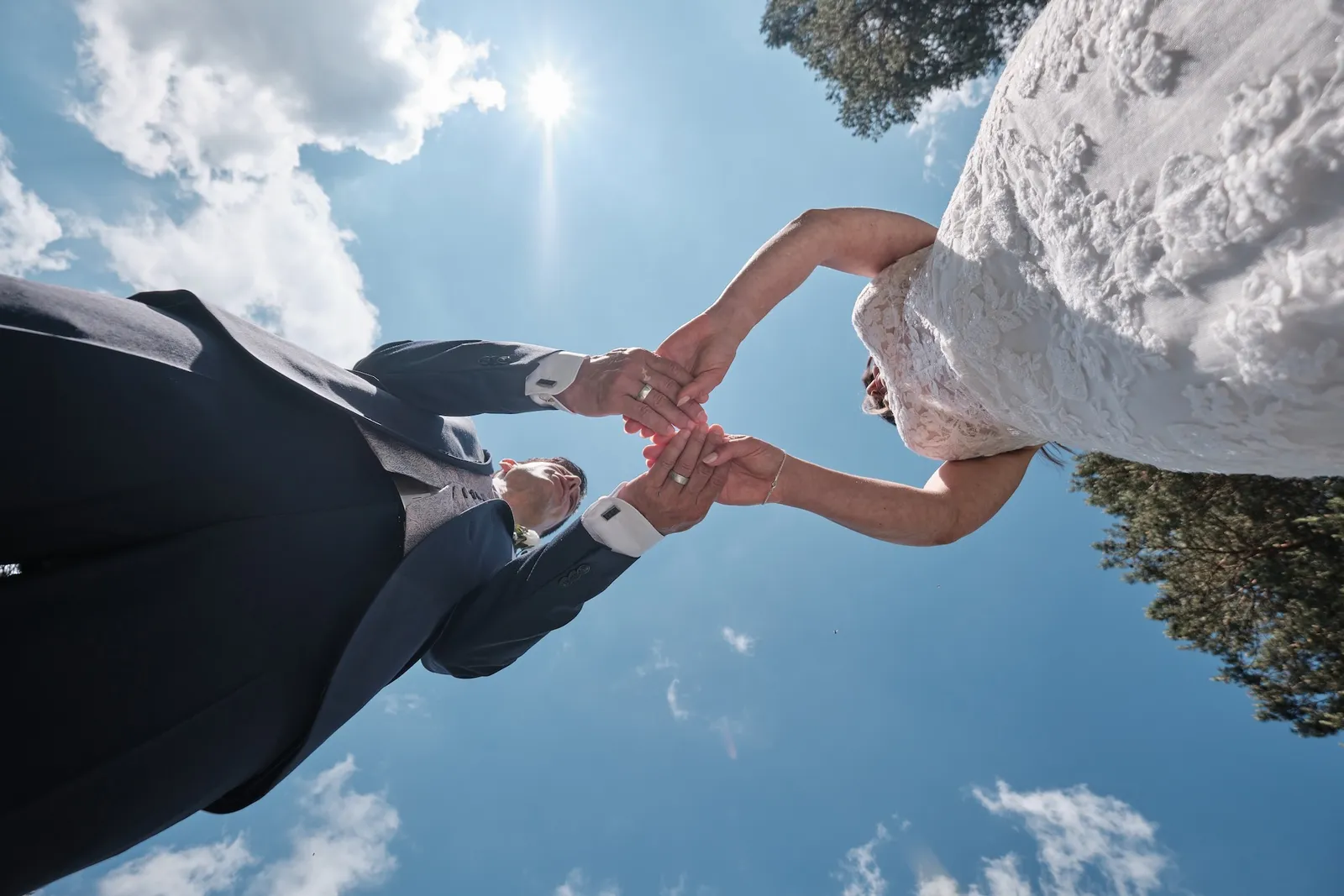 Verschränkte Hände als Herz vor blauem Himmel, von unten fotografiert – Hochzeit Markus & Tanja, Königsbrunner Heide