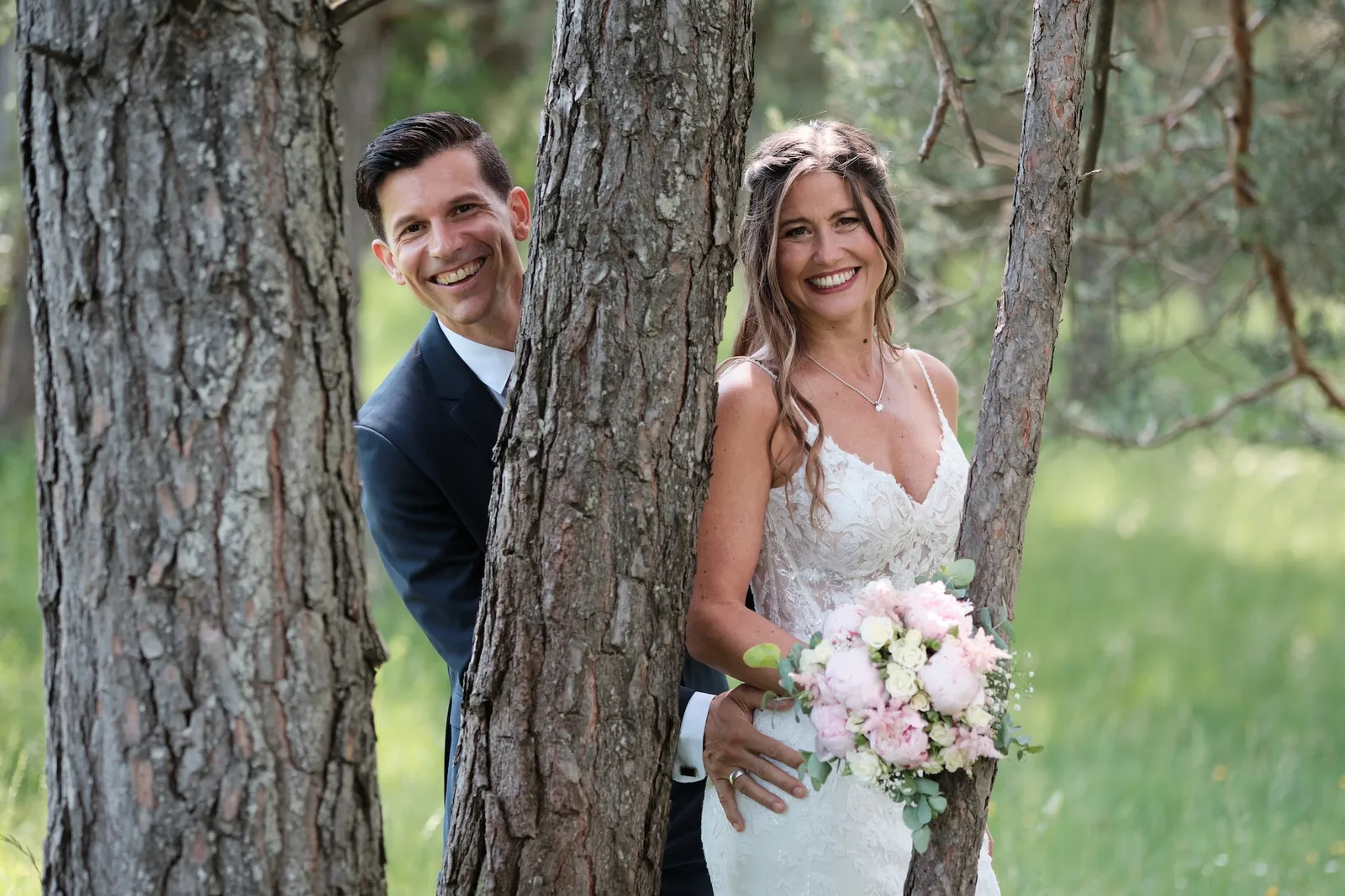 Markus und Tanja lachen zwischen zwei Baumstämmen – Hochzeit Markus & Tanja, Königsbrunner Heide