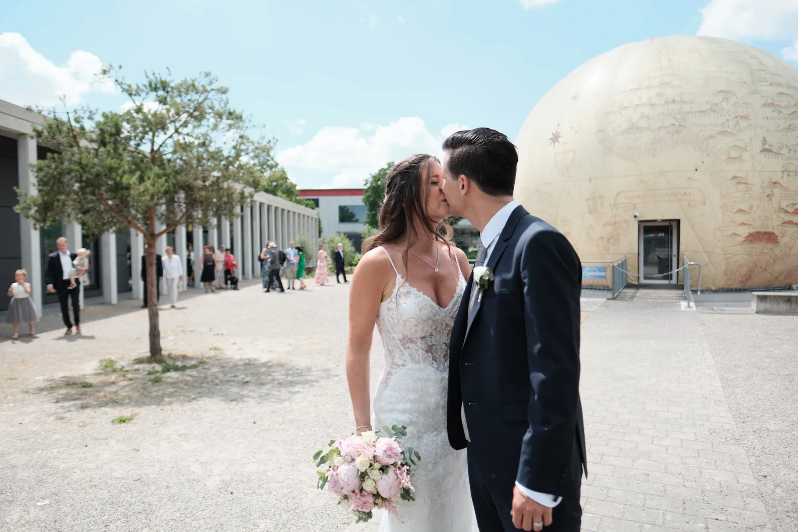 Kuss vor der kugelförmigen Skulptur am Eisstadion – Hochzeit Markus & Tanja, Eisstadion Königsbrunn