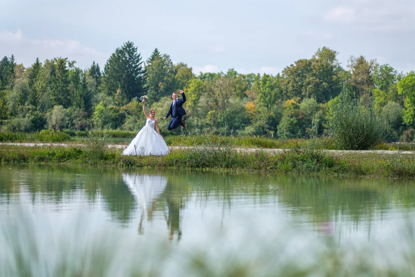 Brautpaar am gegenüberliegenden Seeufer, Spiegelung im Wasser – Hochzeit Alex & Dani