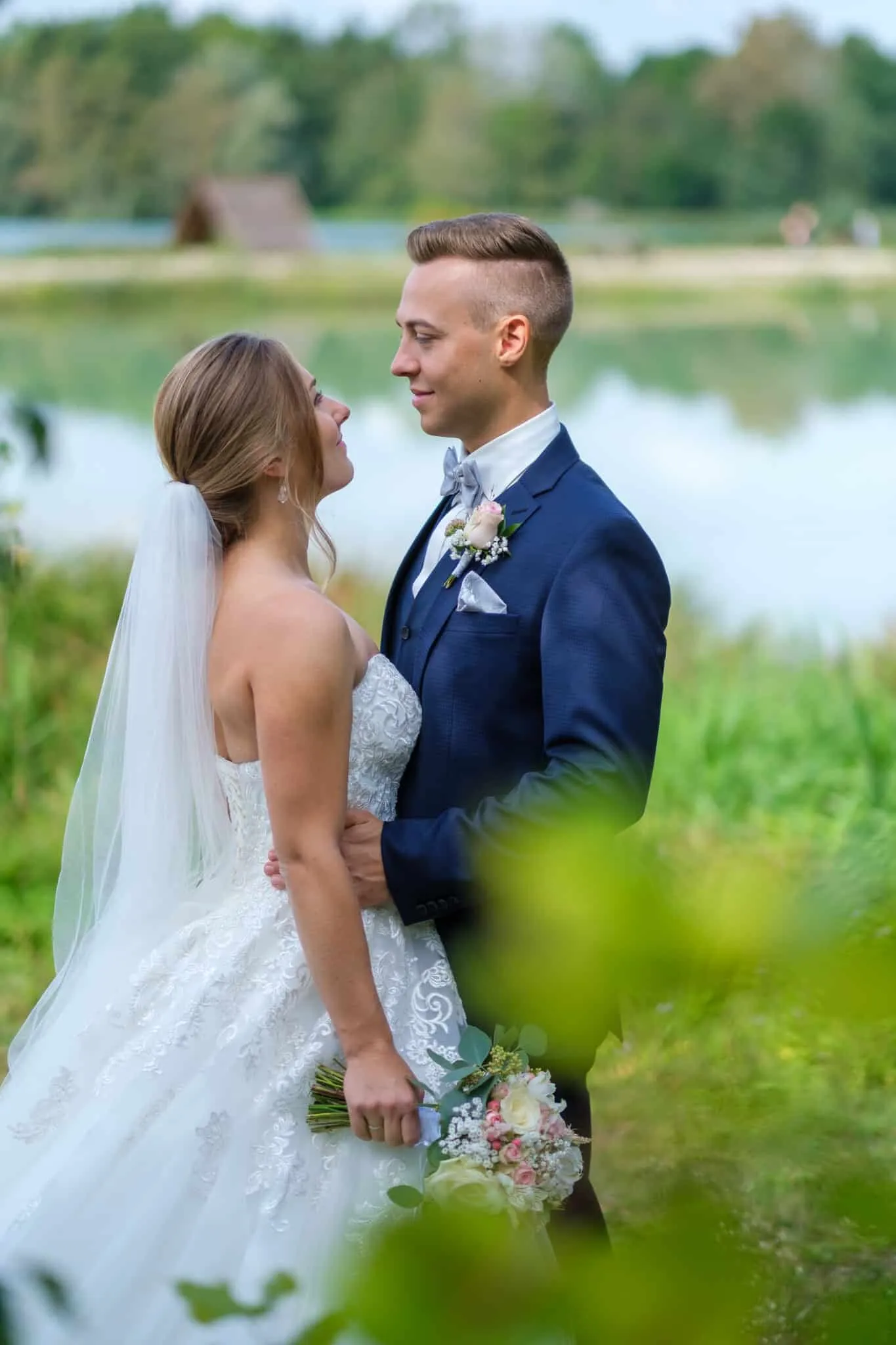 Brautpaar steht umarmt am See und schaut sich an – Hochzeit Alex & Dani