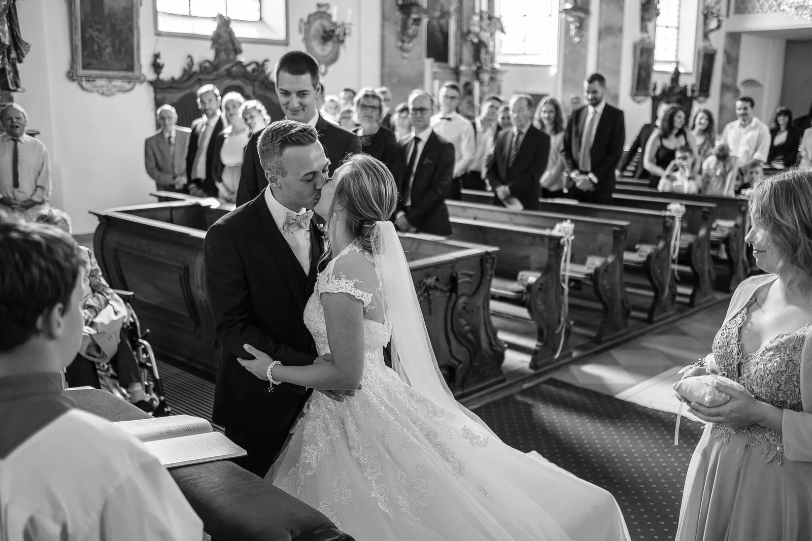 Brautpaar küsst sich in der Kirche vor den Gästen, schwarzweiß – Hochzeit Alex & Dani, Weitmannsee