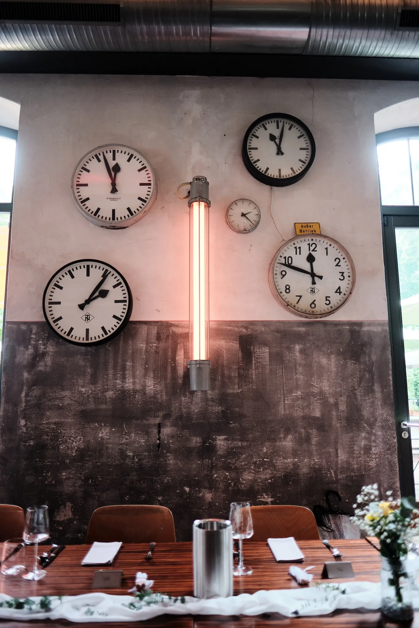 Bahnhofsuhren und gedeckte Tafel im Restaurant der N8Stallung – Hochzeit Svenja & Markus, N8Stallung Augsburg