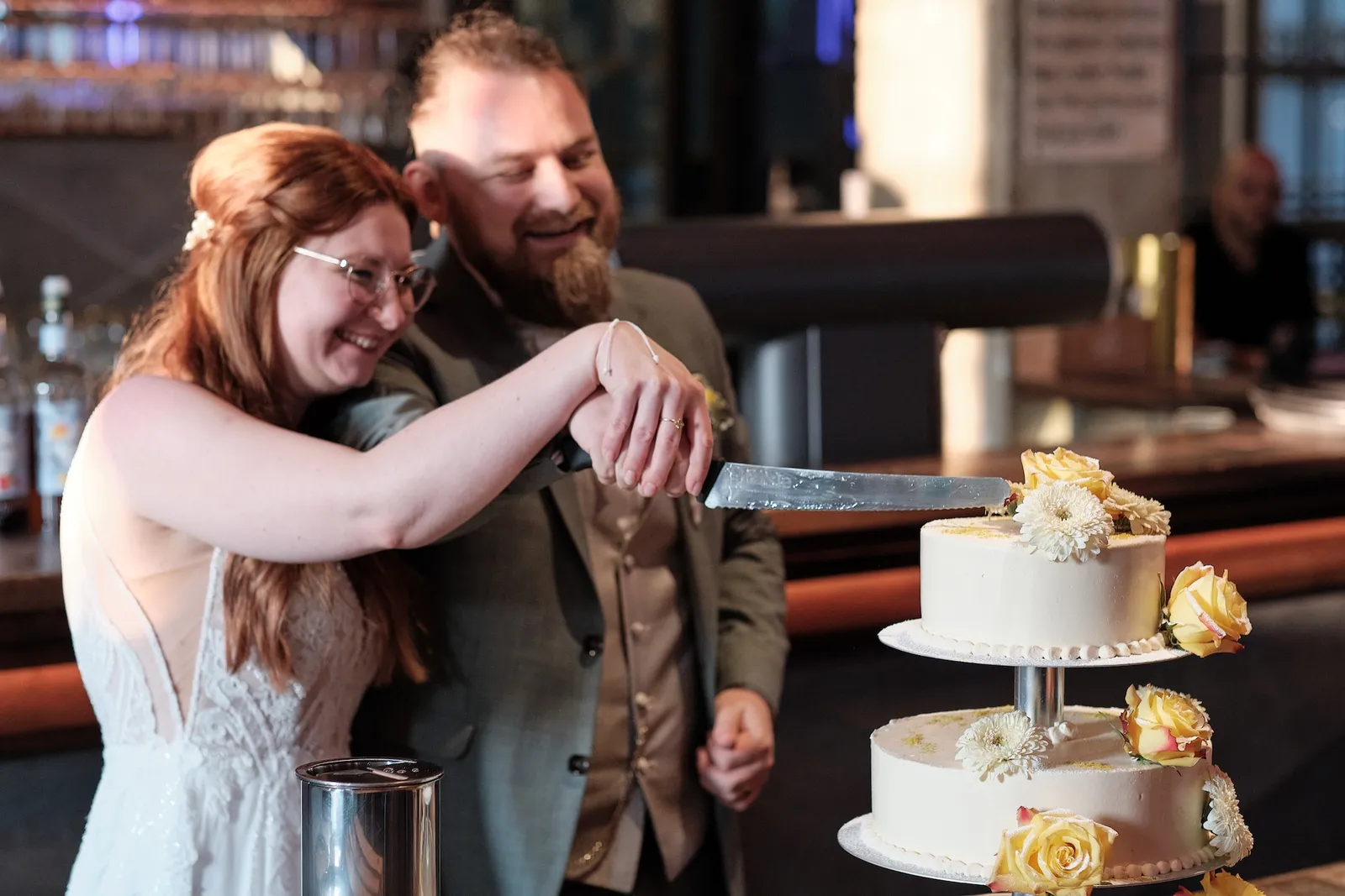 Svenja und Markus schneiden lachend die Hochzeitstorte an – Hochzeit Svenja & Markus, N8Stallung Augsburg