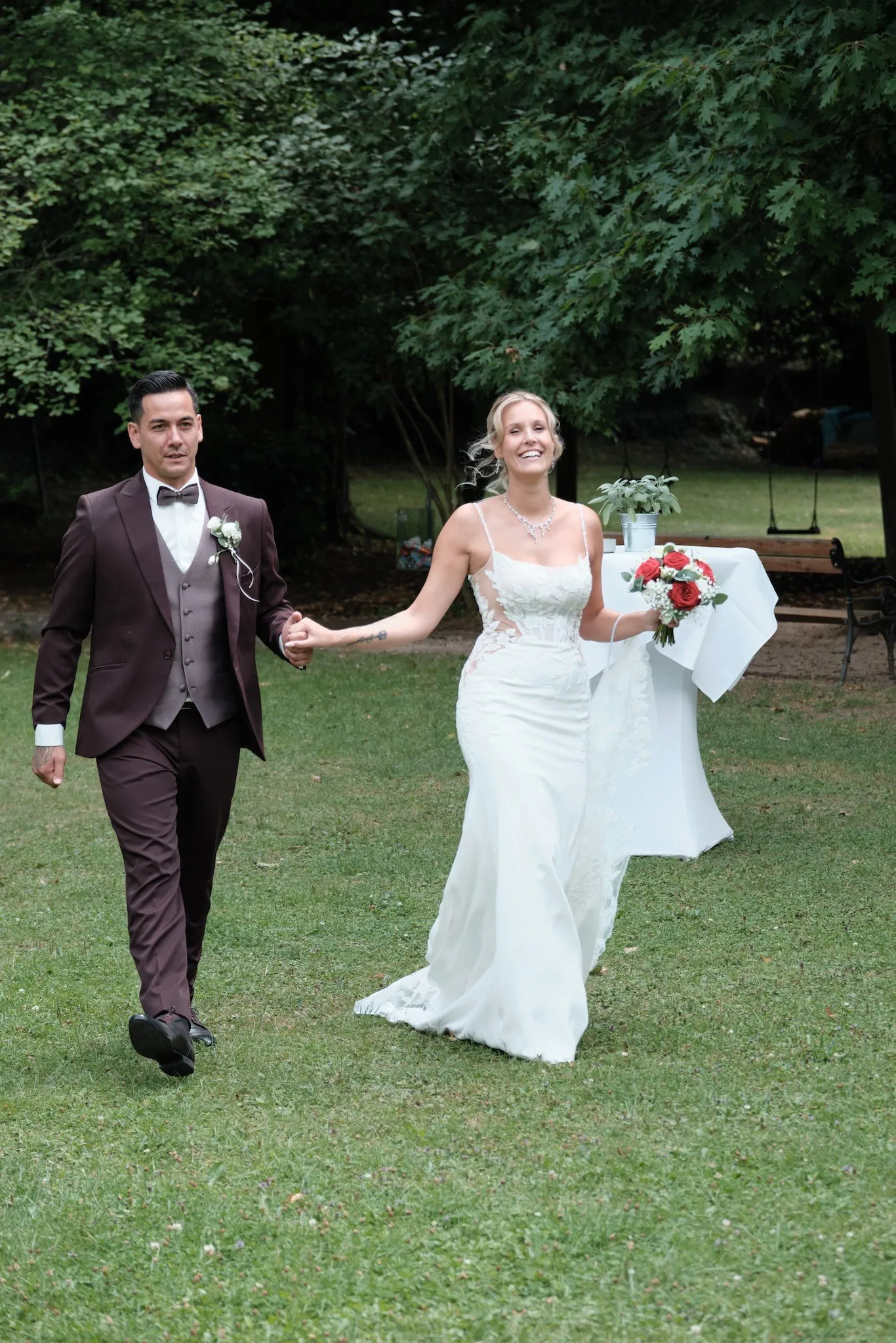 Brautpaar kommt Hand in Hand über die Wiese im Park – Hochzeit Celina & Denny, Parkhotel Schmid Adelsried