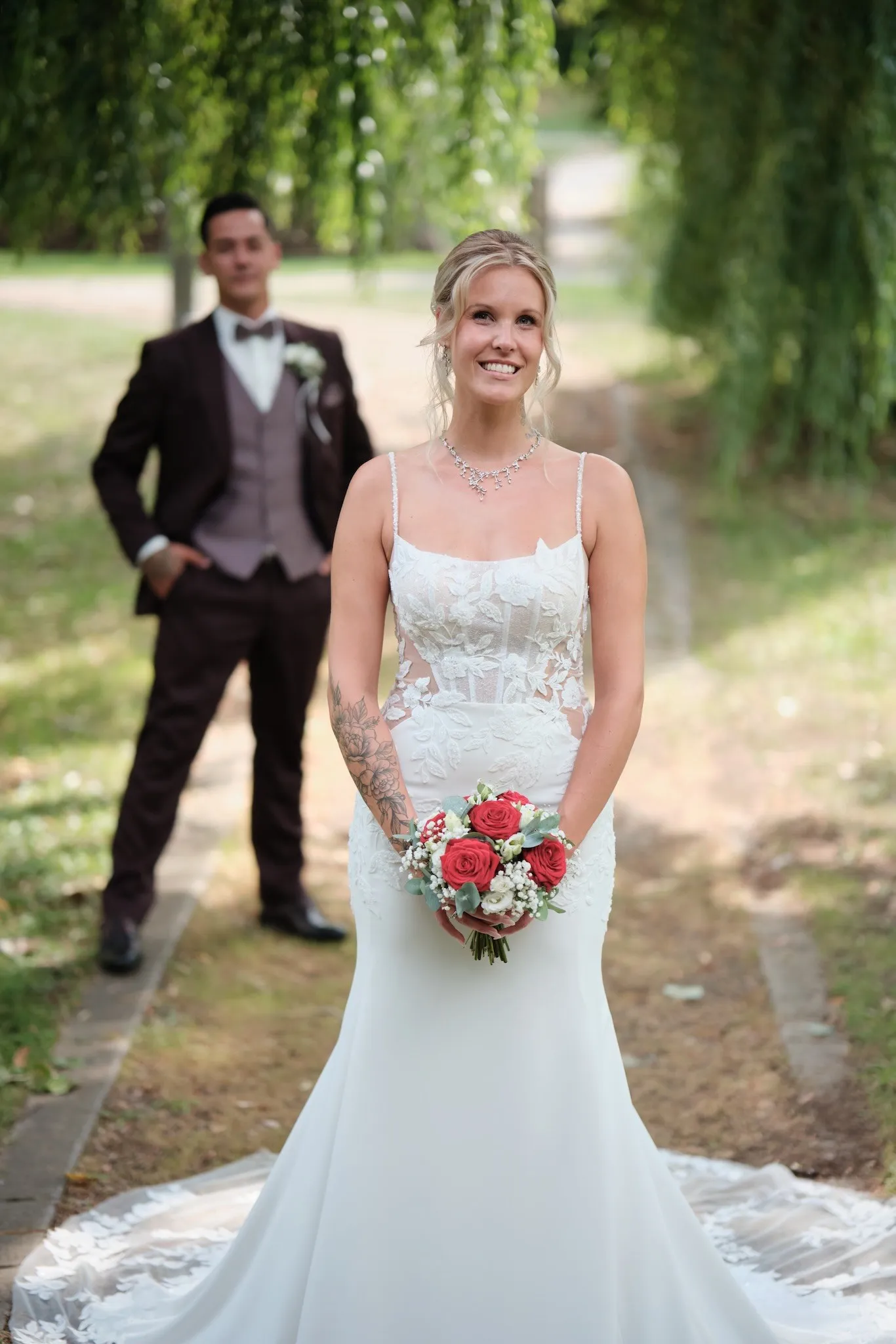 Celina mit Brautstrauß, Denny im Hintergrund – Hochzeit Celina & Denny, Parkhotel Schmid Adelsried