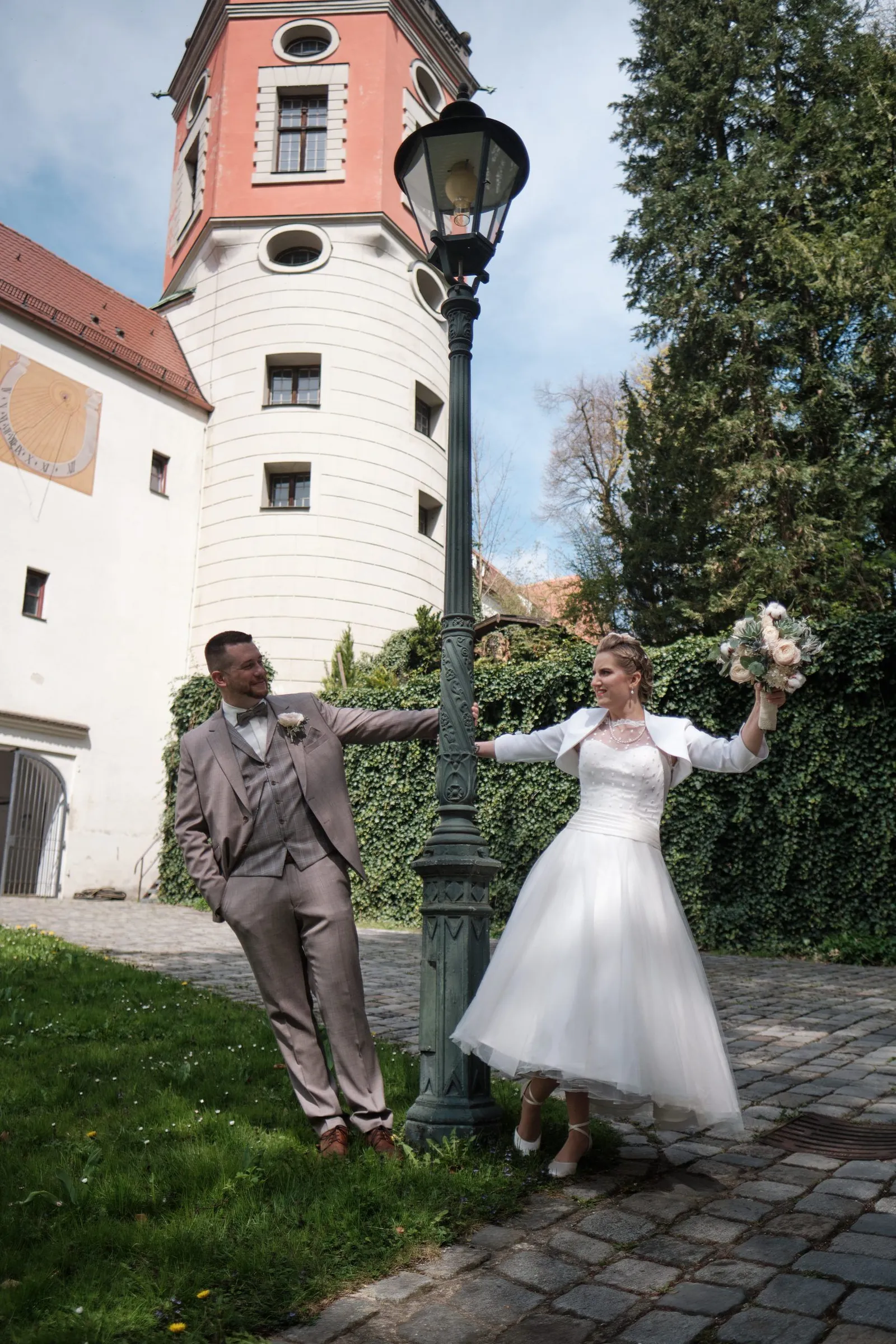 Braut und Bräutigam halten sich an einer Laterne vor einem Turm – Hochzeit Andi & Betti