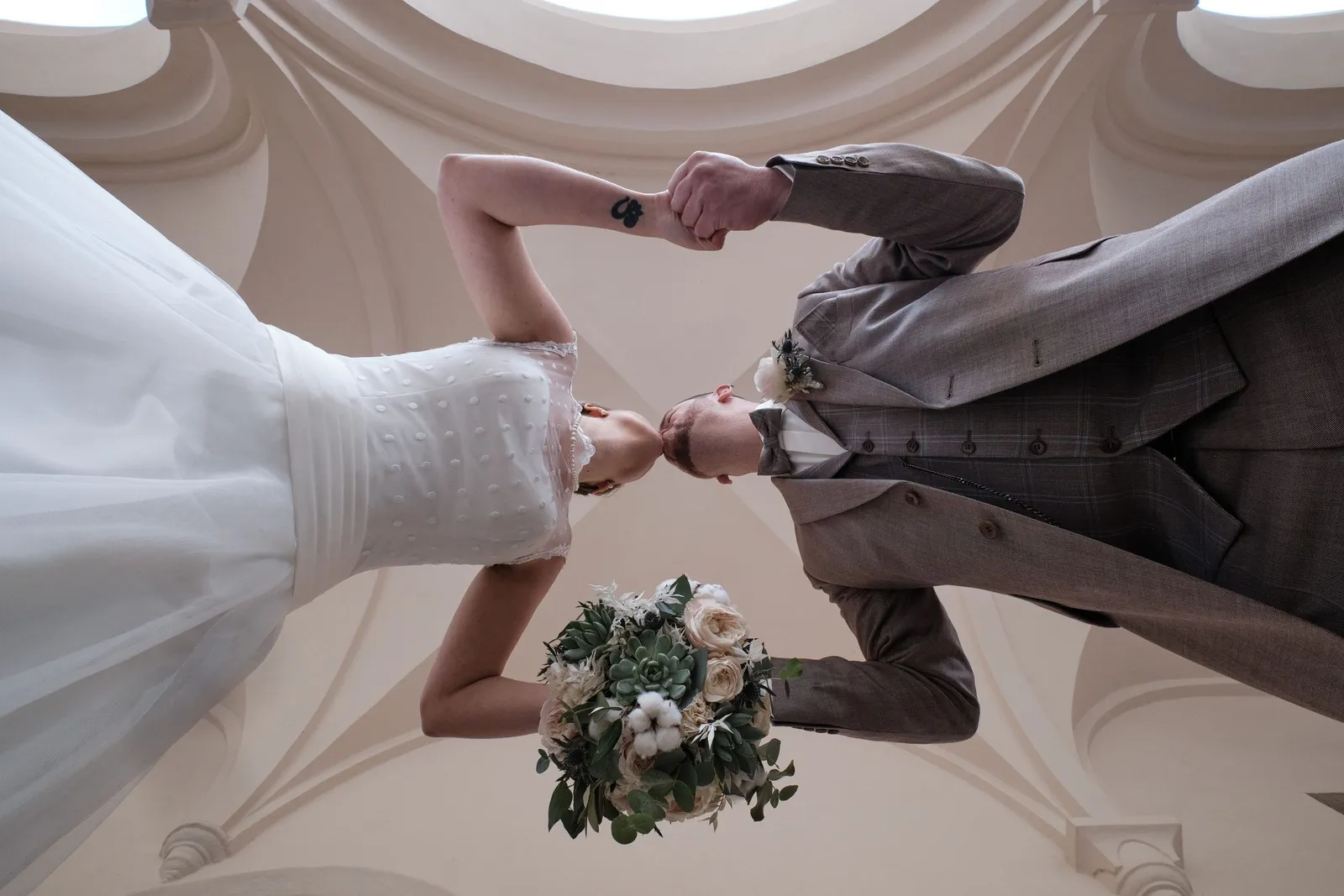 Brautpaar Hand in Hand, von unten unter einer Gewölbedecke fotografiert – Hochzeit Andi & Betti