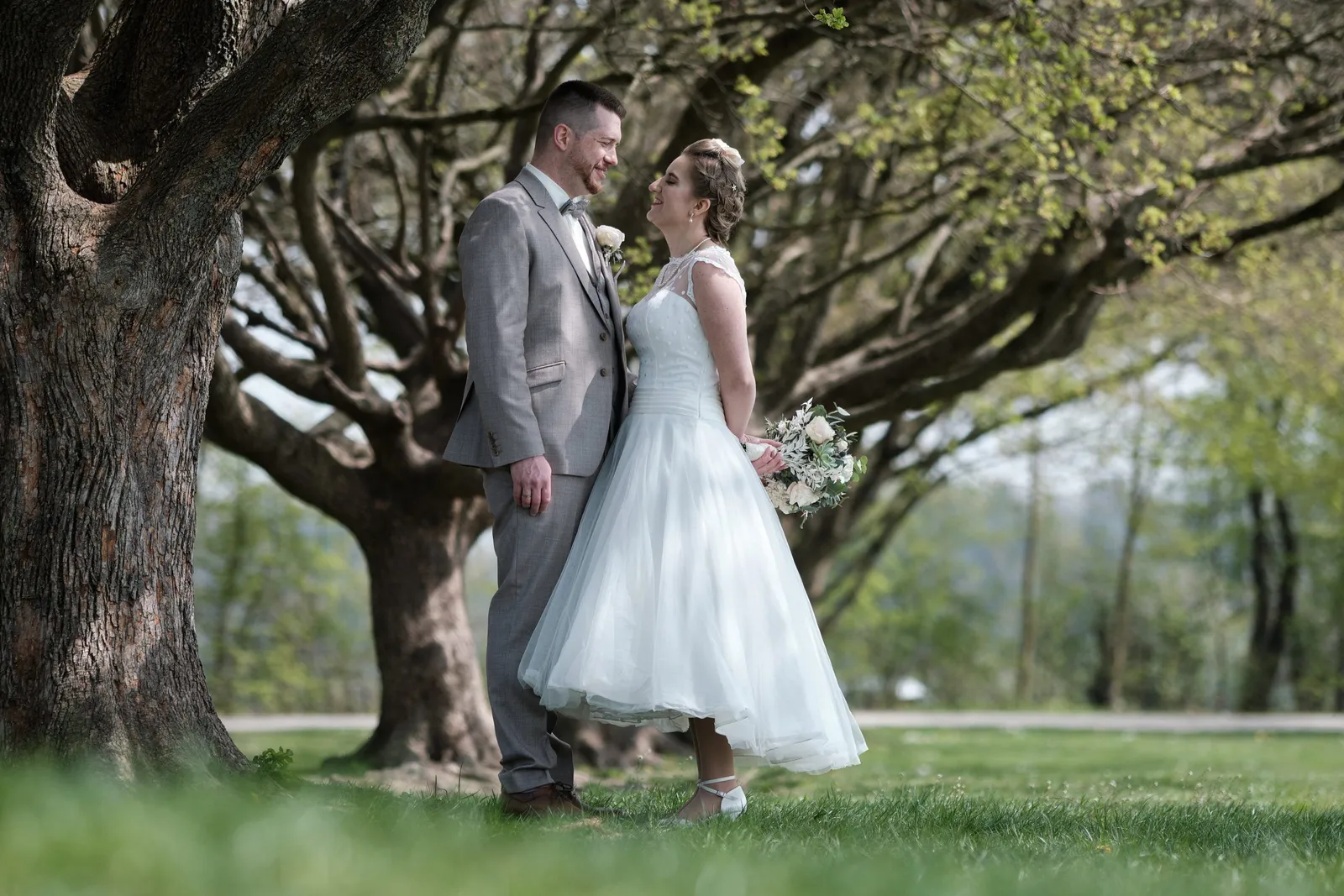 Brautpaar steht sich unter einem großen Baum im Park gegenüber – Hochzeit Andi & Betti