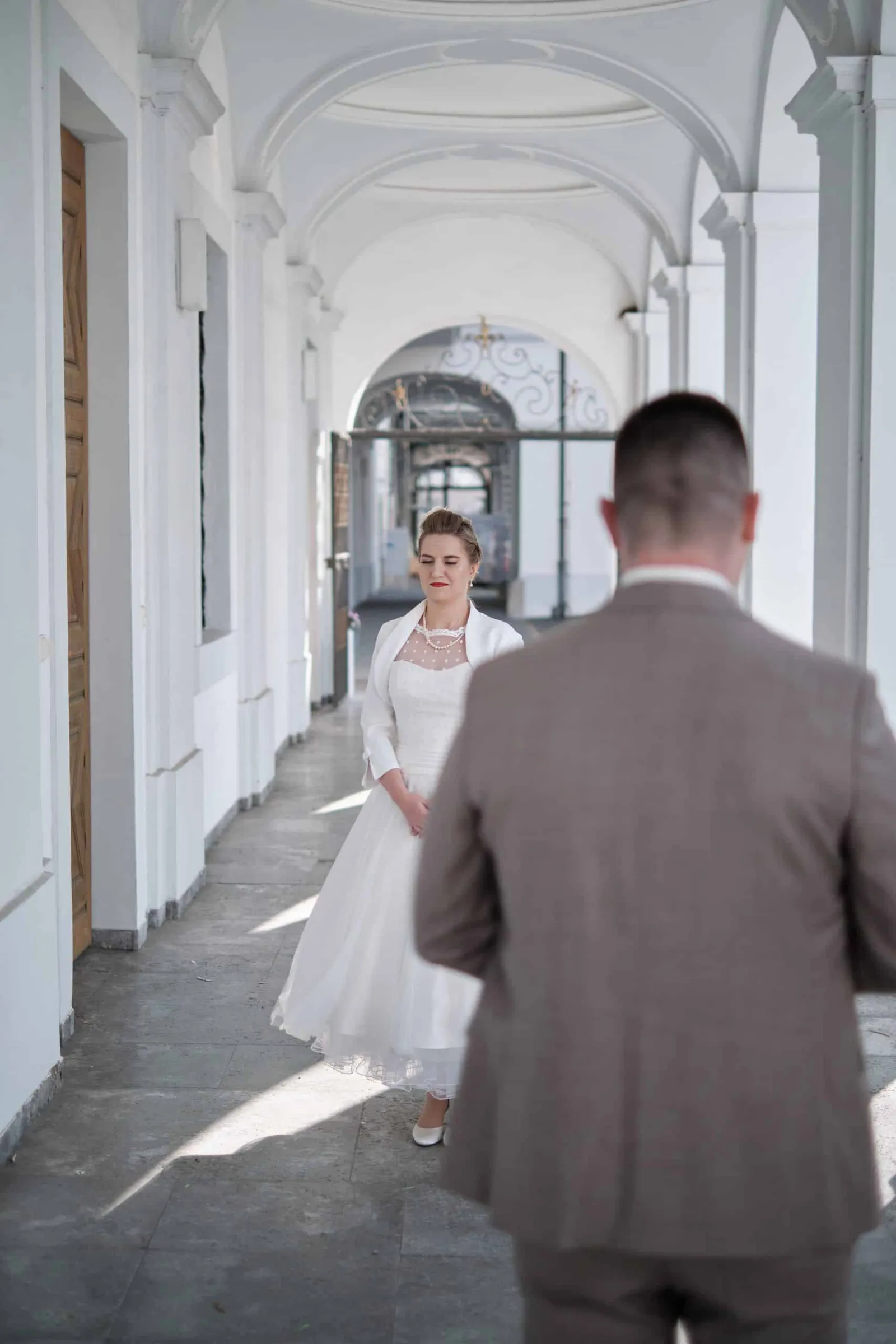 First Look: Braut kommt im Arkadengang auf den Bräutigam zu – Hochzeit Andi & Betti