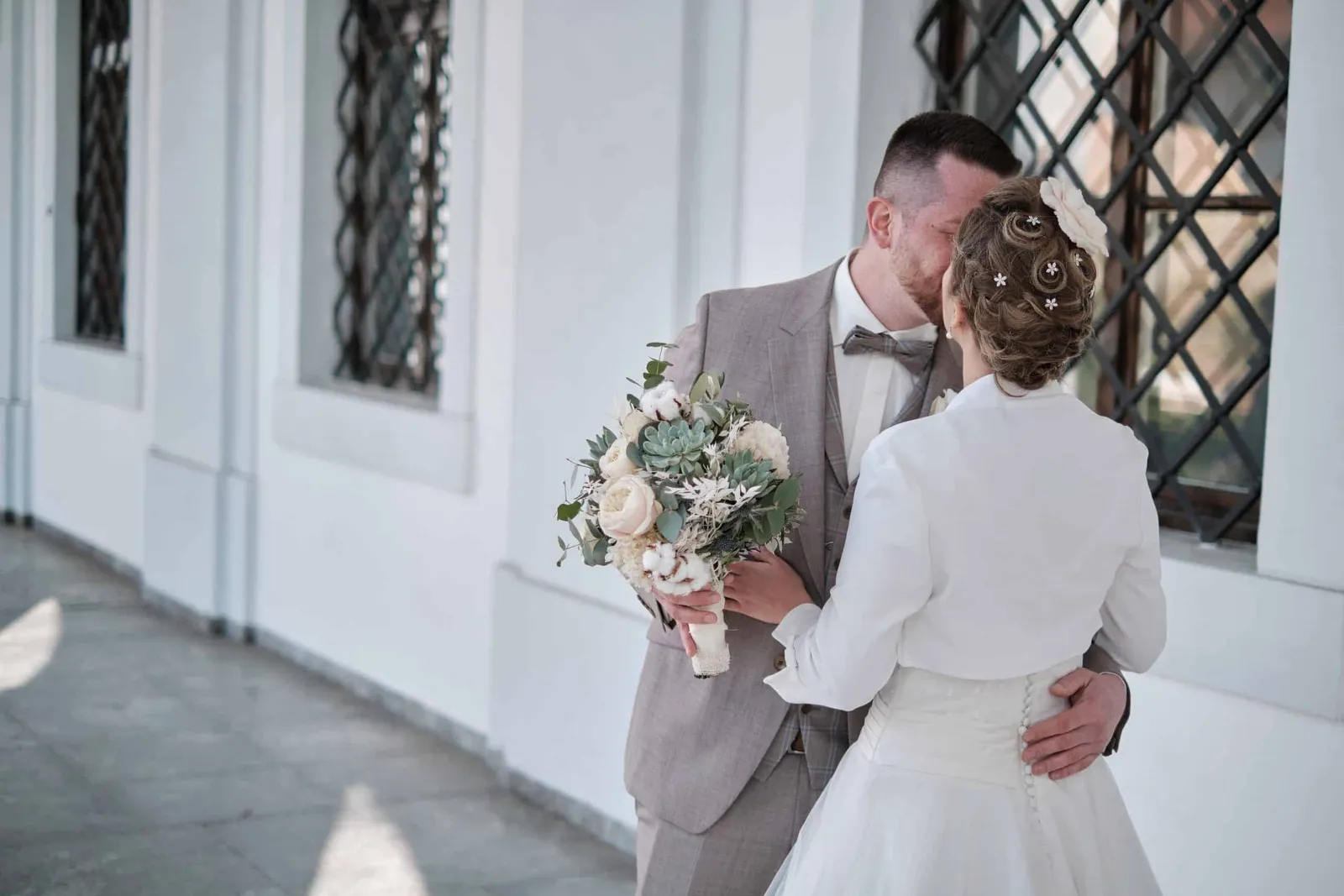 First Look: Brautpaar umarmt sich im Arkadengang – Hochzeit Andi & Betti