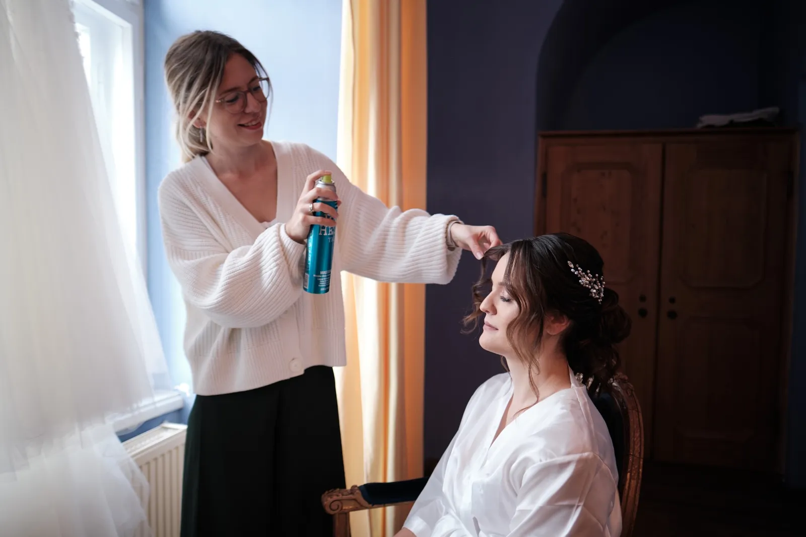 Stylistin sprüht Haarspray auf die Frisur der Braut – Hochzeit Barbara & Christian, Schloss Neuburg a.d. Kammel