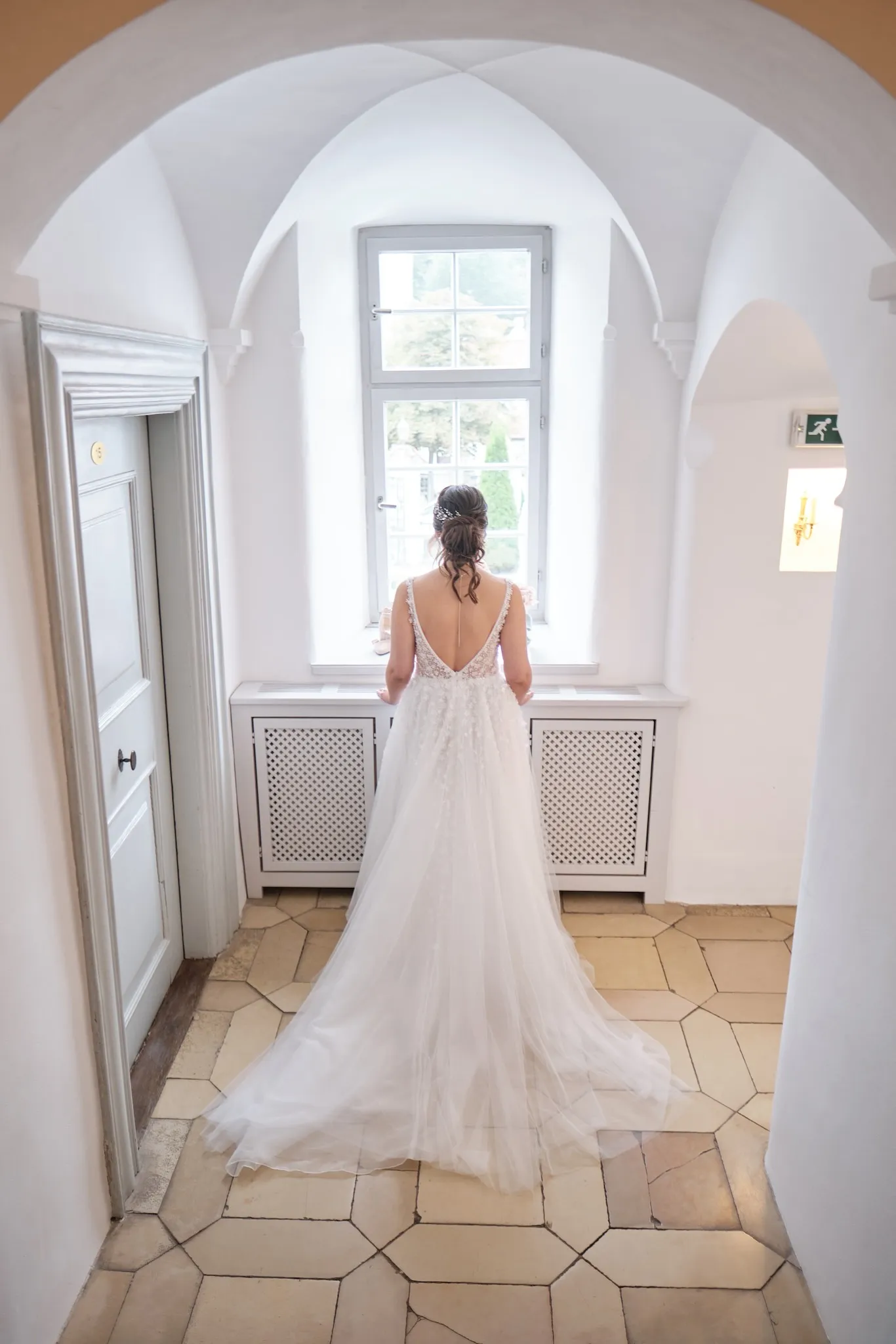 Braut von hinten im Kleid in einem gewölbten Gang des Schlosses – Hochzeit Barbara & Christian, Schloss Neuburg a.d. Kammel