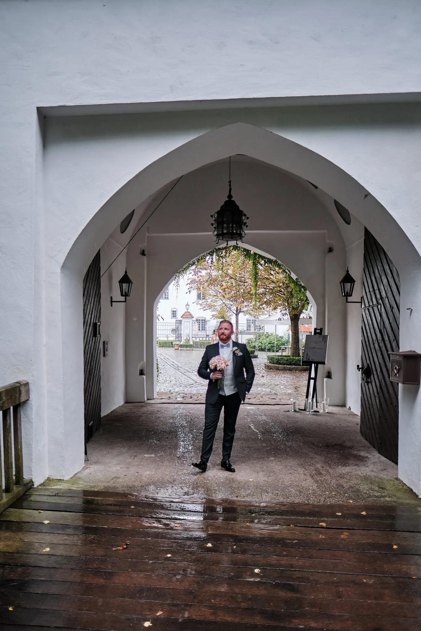 Bräutigam wartet allein im Torbogen auf den First Look – Hochzeit Barbara & Christian, Schloss Neuburg a.d. Kammel