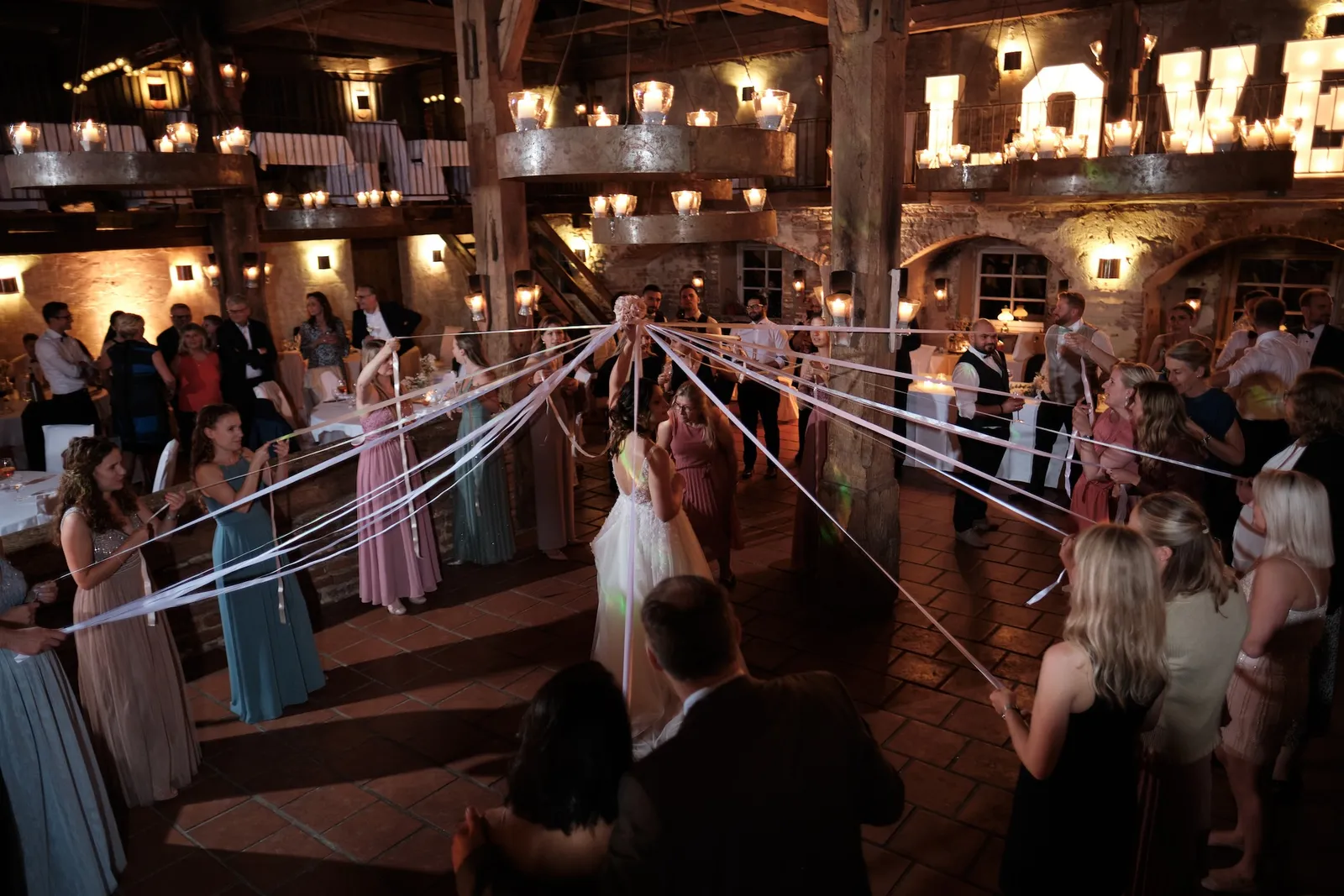 Gäste beim Bänder-Spiel mit dem Brautpaar in der Mitte – Hochzeit Barbara & Christian, Schloss Neuburg a.d. Kammel