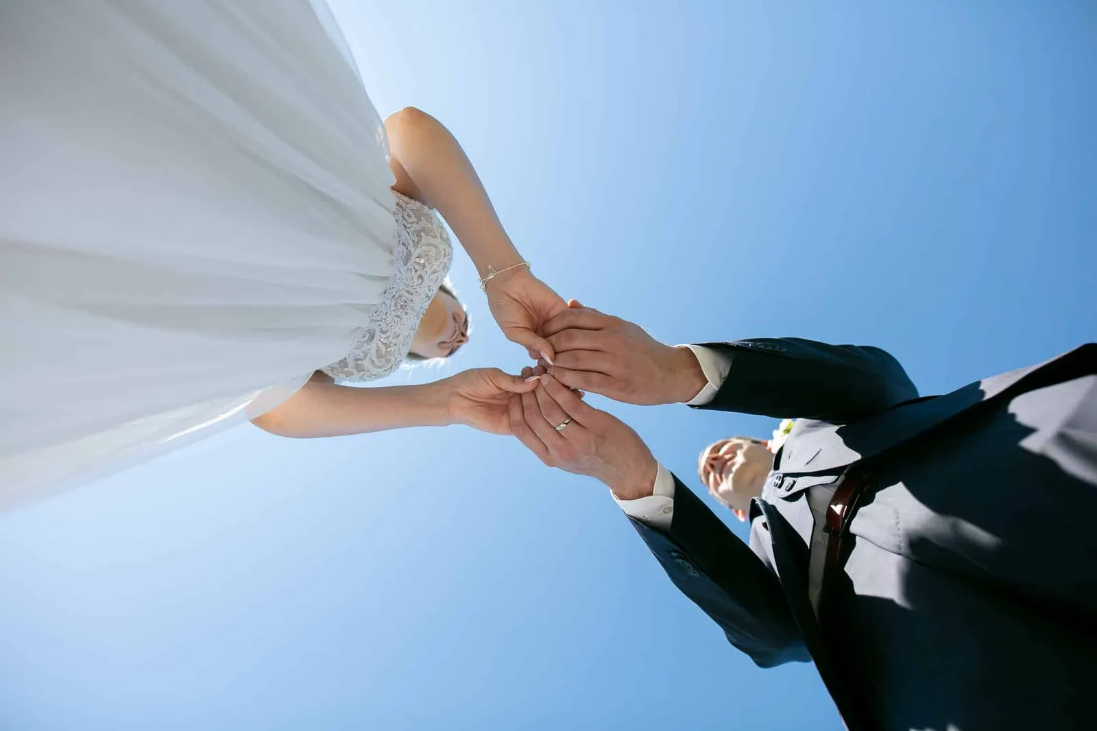Hände des Brautpaars vor blauem Himmel, von unten fotografiert – Hochzeit Andreas & Nicole