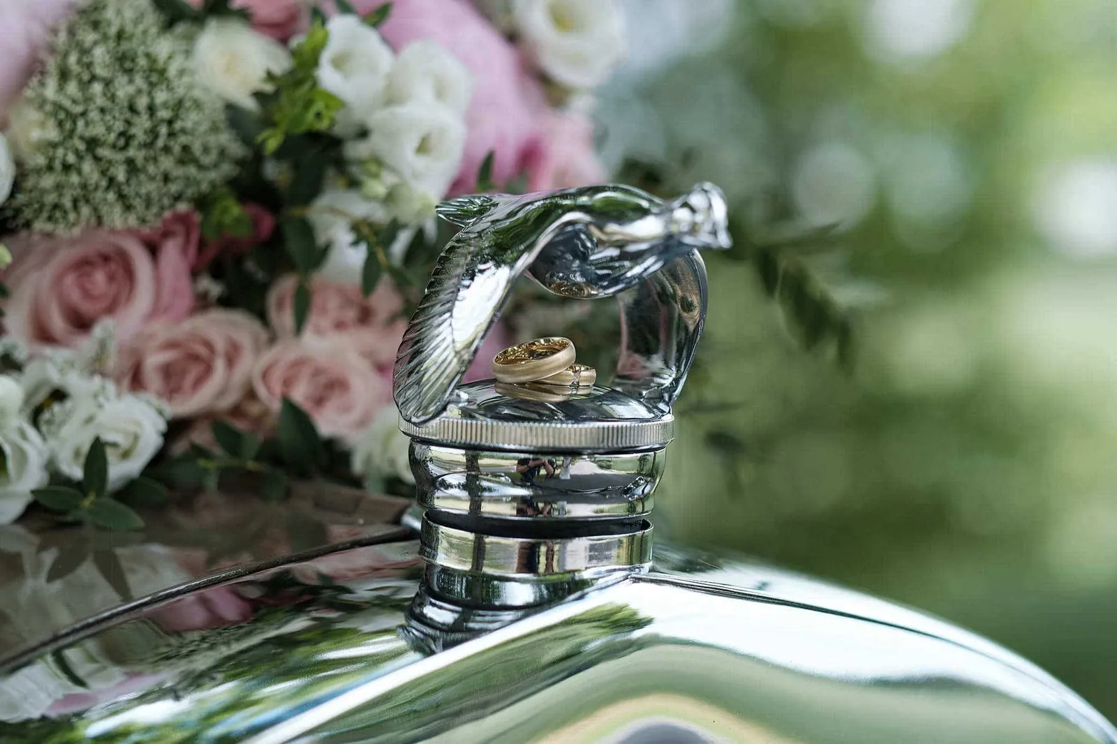 Eheringe auf der Kühlerfigur eines Oldtimers neben dem Brautstrauß – Hochzeit Jessie & Kosta, Wellenburger Allee