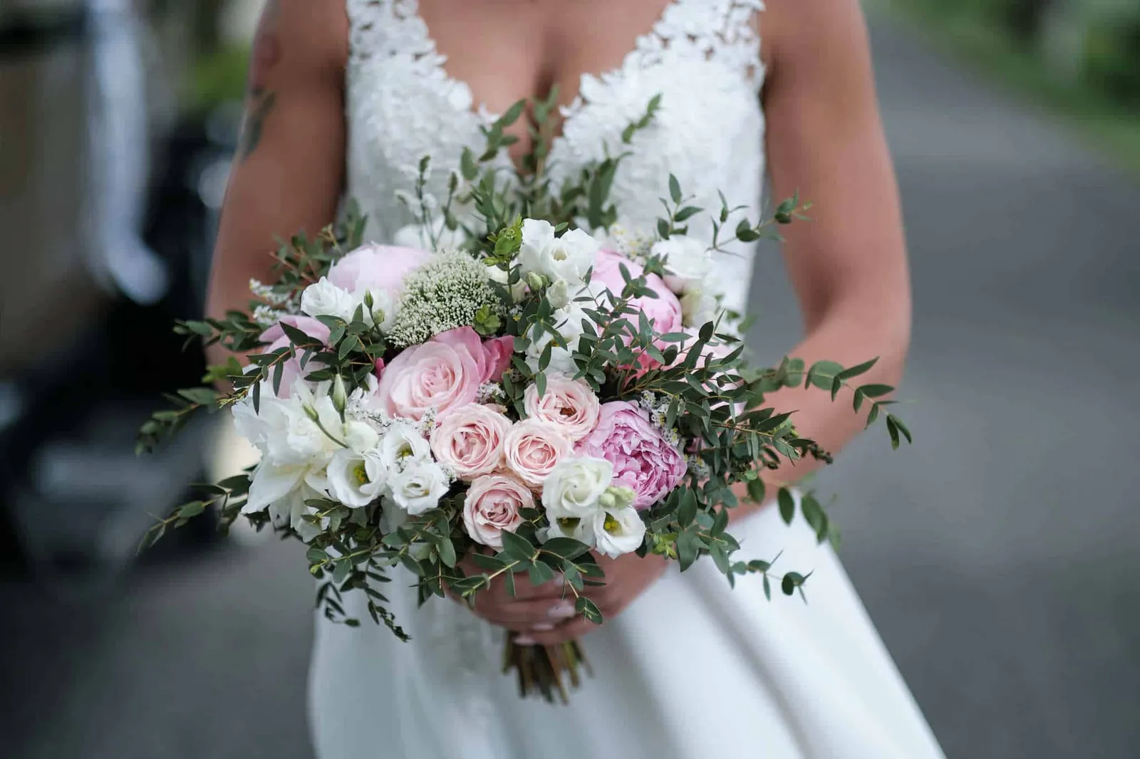 Brautstrauß mit rosa Rosen und Pfingstrosen vor dem weißen Brautkleid – Hochzeit Jessie & Kosta, Wellenburger Allee