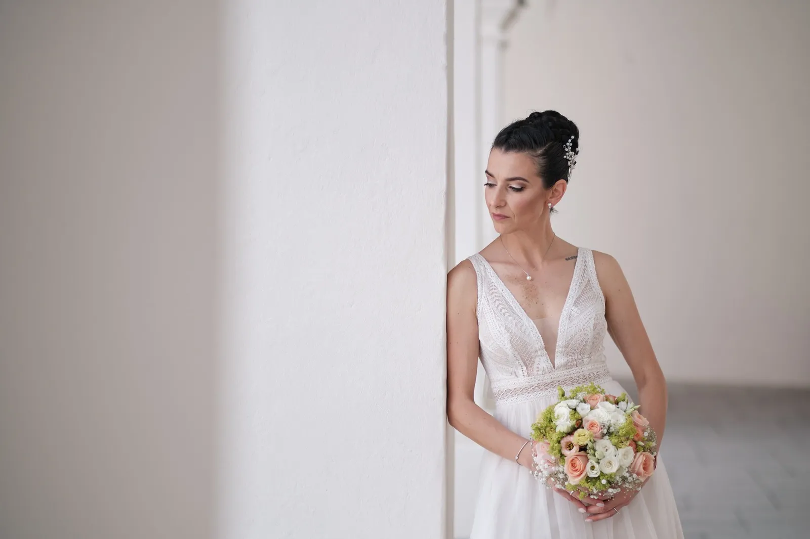 Nina mit ihrem Brautstrauß an einer weißen Schlosswand – Hochzeit Martin & Nina, Wittelsbacher Schloss Friedberg