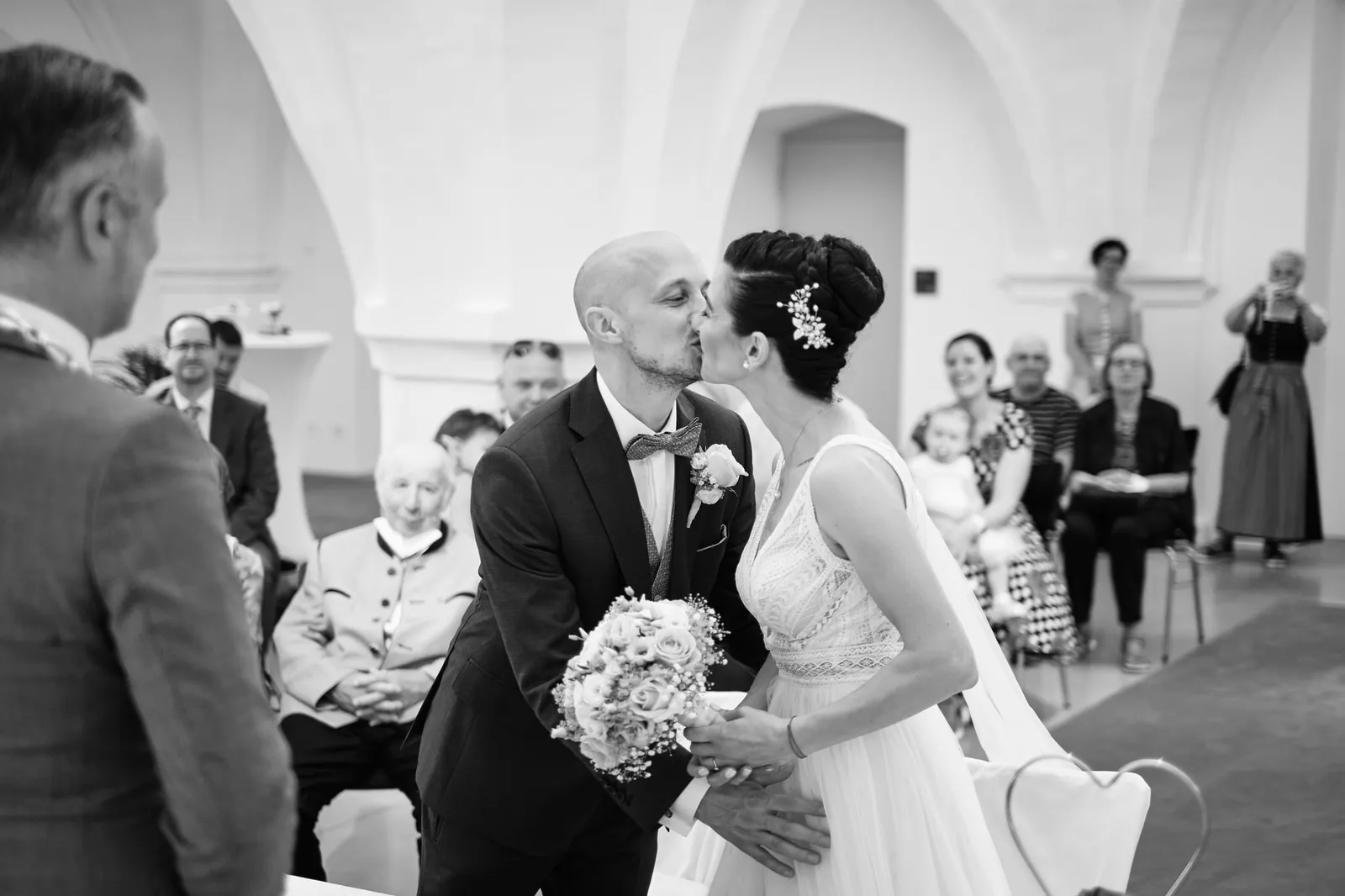 Der erste Kuss als Ehepaar, im Hintergrund die Gäste – Hochzeit Martin & Nina, Wittelsbacher Schloss Friedberg
